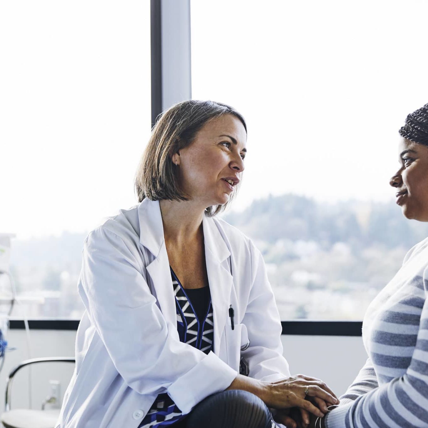 Smiling Doctor Talking To Young Woman In Hospital Smiling Doctor Talking To Young Woman In Hospital